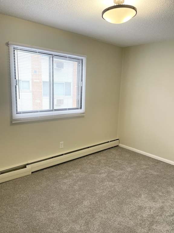 A room with a carpeted floor and a window with blinds.