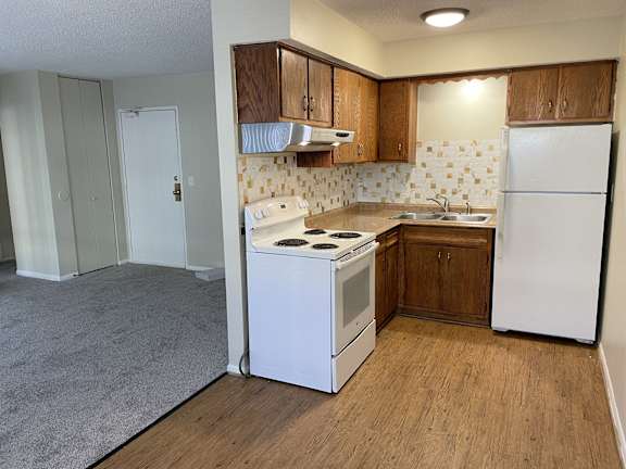 A kitchen with white appliances and wooden cabinets.