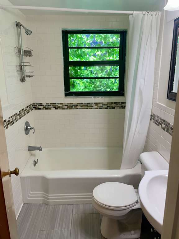 A white toilet sits next to a bathtub in a bathroom.