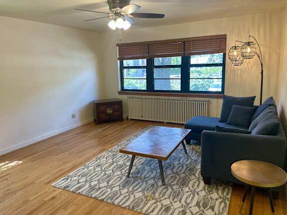 A living room with a blue couch, a wooden coffee table, and a ceiling fan.