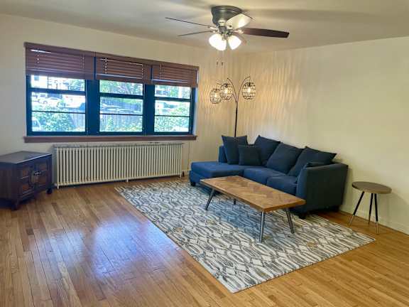 A living room with a blue couch and a wooden floor.