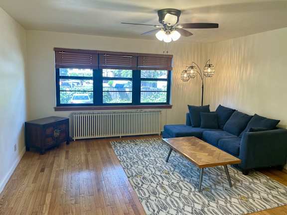 A living room with a blue couch, a wooden coffee table, and a ceiling fan.
