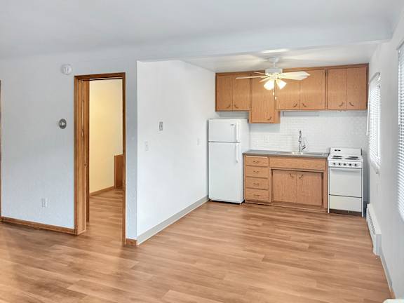 A kitchen with white appliances and wooden cabinets.