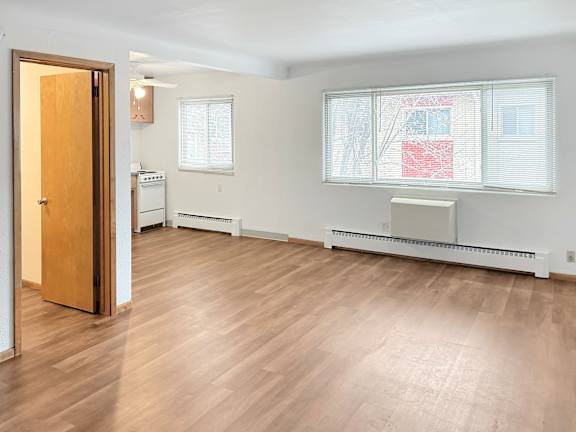 A room with a wooden floor and a window with blinds.