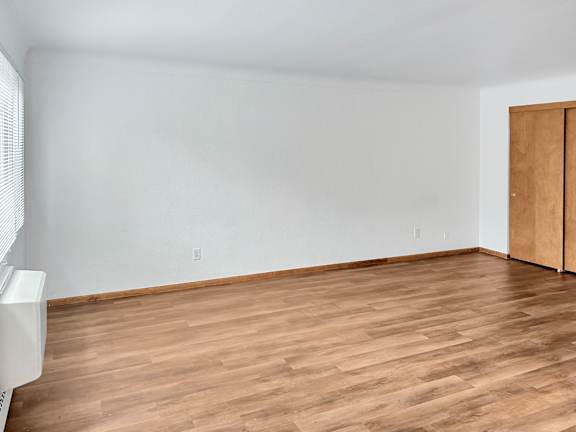 A room with wooden flooring and a white wall.