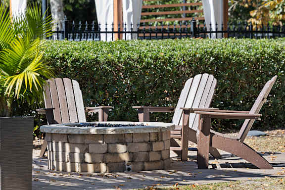 Two chairs and a table are in front of a hedge.