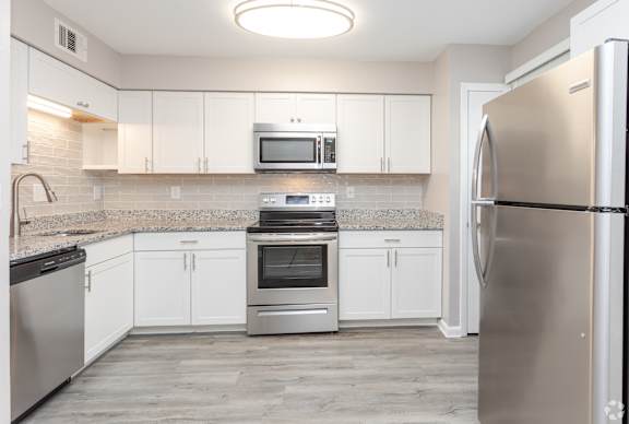 A kitchen with white cabinets and stainless steel appliances.