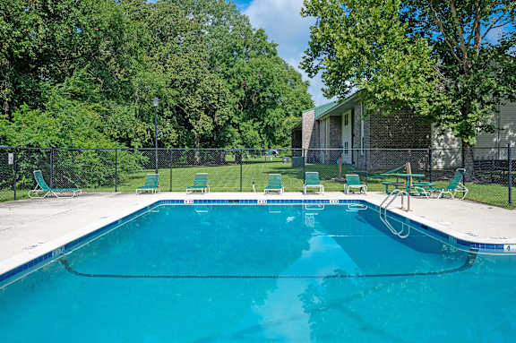 A swimming pool surrounded by trees and chairs at Sawbranch Apartments, Summerville, SC, 29485