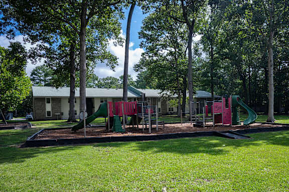 A playground with a green slide and red and green swings at Sawbranch Apartments, Summerville