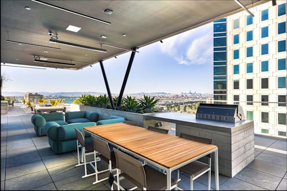 A rooftop patio with a table and chairs overlooking a cityscape.