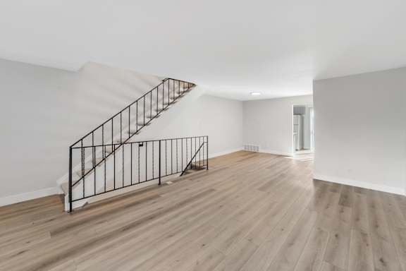 A wooden staircase with a metal railing leads to a second floor. at The Lex At Lowry, Denver, 80224
