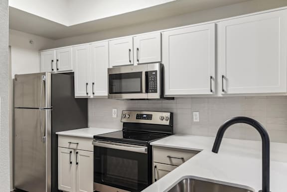 A kitchen with white cabinets and black appliances.at Onyx183, Austin, TX