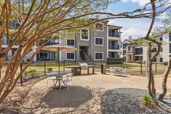 A courtyard with a picnic table surrounded by trees and apartment buildings.at Onyx183, Austin