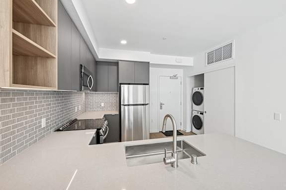 A modern kitchen with a stainless steel refrigerator and a sink.