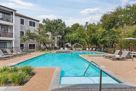 A swimming pool surrounded by lounge chairs and trees.at Onyx183, Austin, 78729