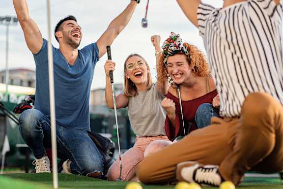 A group of people are playing mini golf and having a great time at Coro Apartments, Los Angeles, 90016