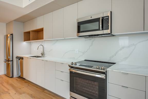 A modern kitchen with a stainless steel refrigerator, microwave, and oven.at Prizma, Los Angeles