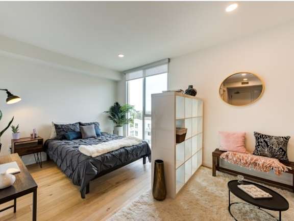A bedroom with a bed, a bench, and a mirror on the wall.at Prizma, Los Angeles California