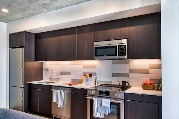 A modern kitchen with dark wood cabinets and stainless steel appliances.at Eleven Fifty Clay Street, Oakland, 94607