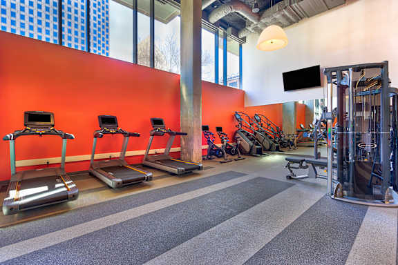 A gym with treadmills, weights and a television.at Eleven Fifty Clay Street, Oakland