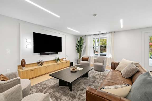A modern living room with a brown leather couch and a flat screen TV mounted on the wall.
