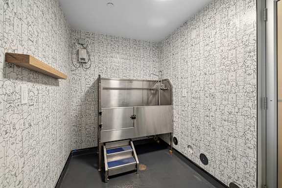 A wallpapered room with a metal fridge and a step ladder.