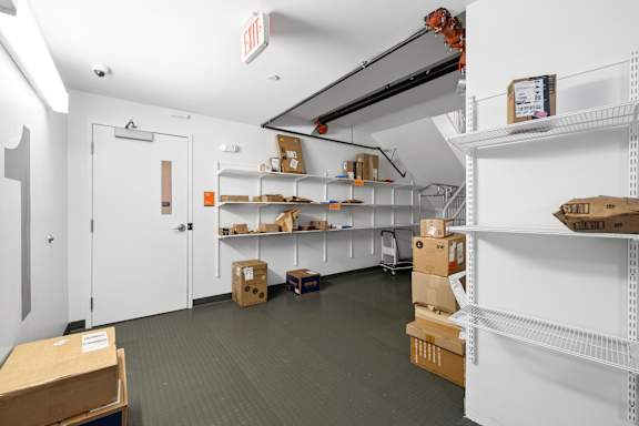 A storage room with white shelves and boxes on the floor.