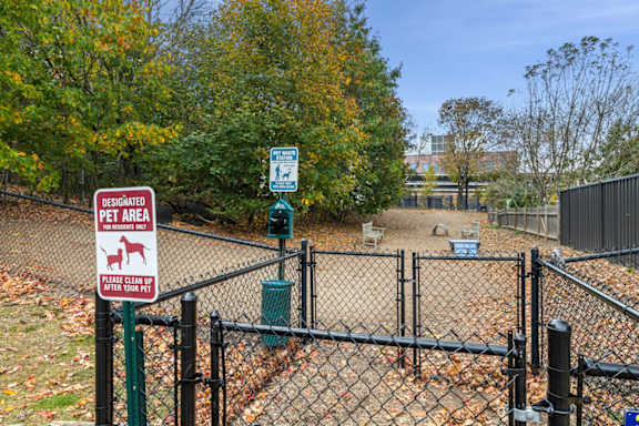 A sign in a fenced area indicates it is a designated pet area.