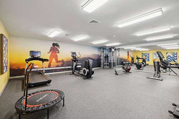 A gym with a variety of equipment including treadmills, exercise bikes, and weights.
