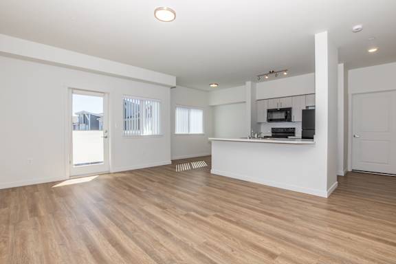 A spacious room with wooden floors and white walls.