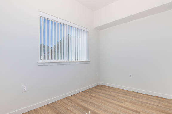 A room with a window and wooden flooring.