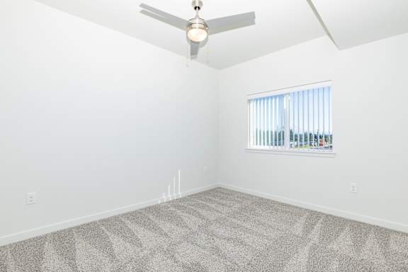 A room with a ceiling fan and a window with blinds.