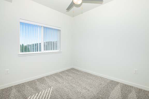 A room with a carpeted floor and a window with blinds.