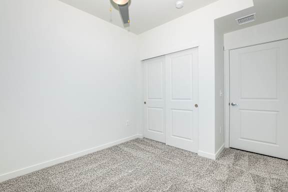 A room with two doors and a ceiling fan.