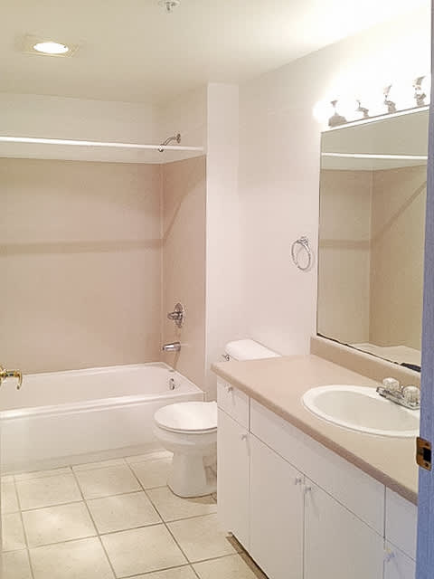 A white bathroom with a toilet, sink, and mirror.