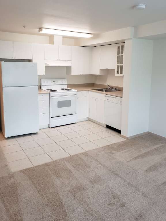 A kitchen with white appliances and cabinets.