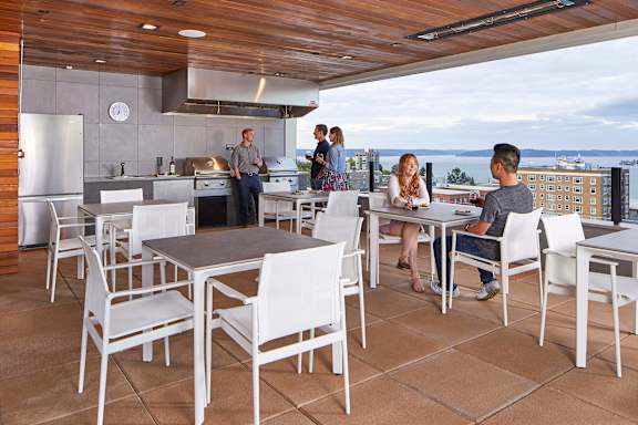 A group of people are gathered around a table in a modern outdoor kitchen.