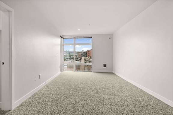 A large empty room with a window overlooking a cityscape.
