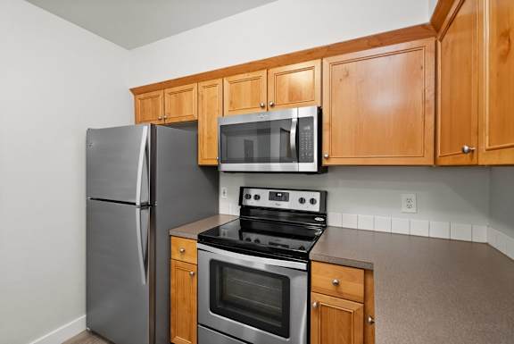 A kitchen with a stove, oven, refrigerator and microwave.