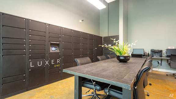 A room with a table, chairs and a wall with the word LUXER on it.