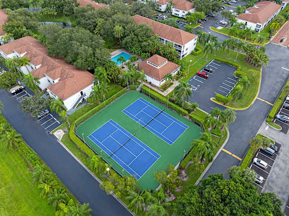 A tennis court surrounded by houses and trees.