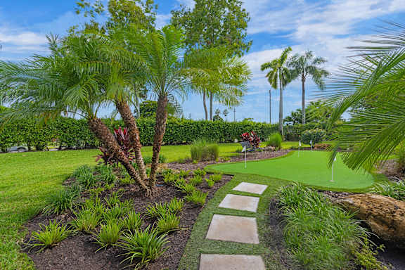 A garden with a pathway and a palm tree.