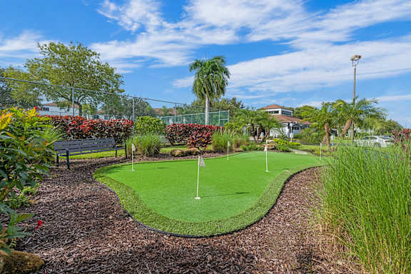 A small putting green is surrounded by a garden.