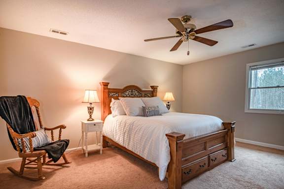 A bedroom with a bed, a chair, and two lamps.