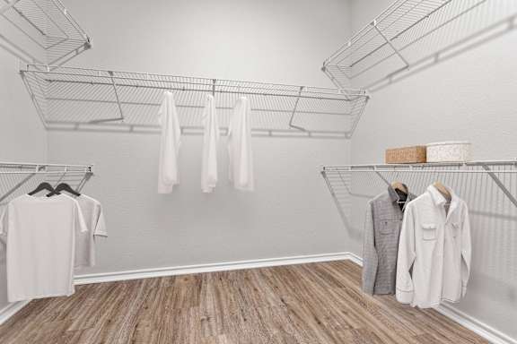 A white shirt is hanging on a rack in a room with wooden floors.