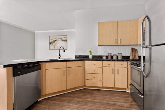 A kitchen with wooden cabinets and a black countertop.