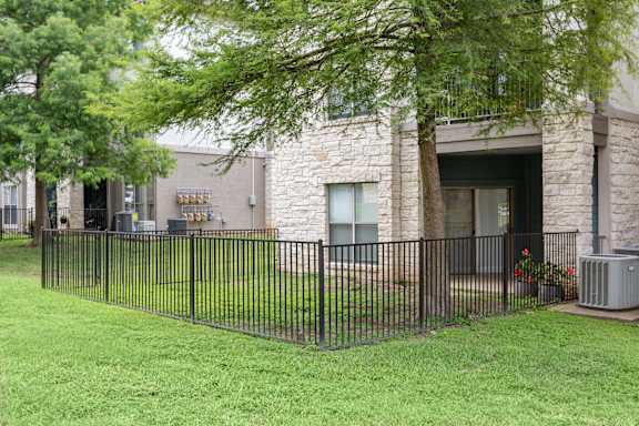 A black iron fence surrounds a green lawn.