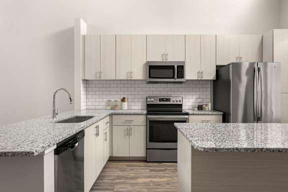 A kitchen with a granite countertop and stainless steel appliances.