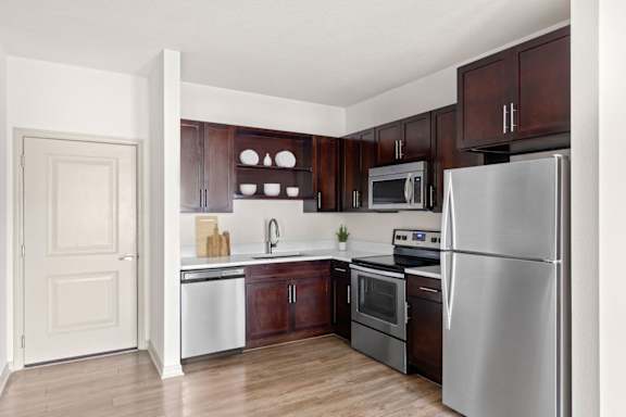 A kitchen with a refrigerator, oven, and sink.