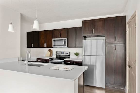 A modern kitchen with a white countertop and stainless steel appliances.